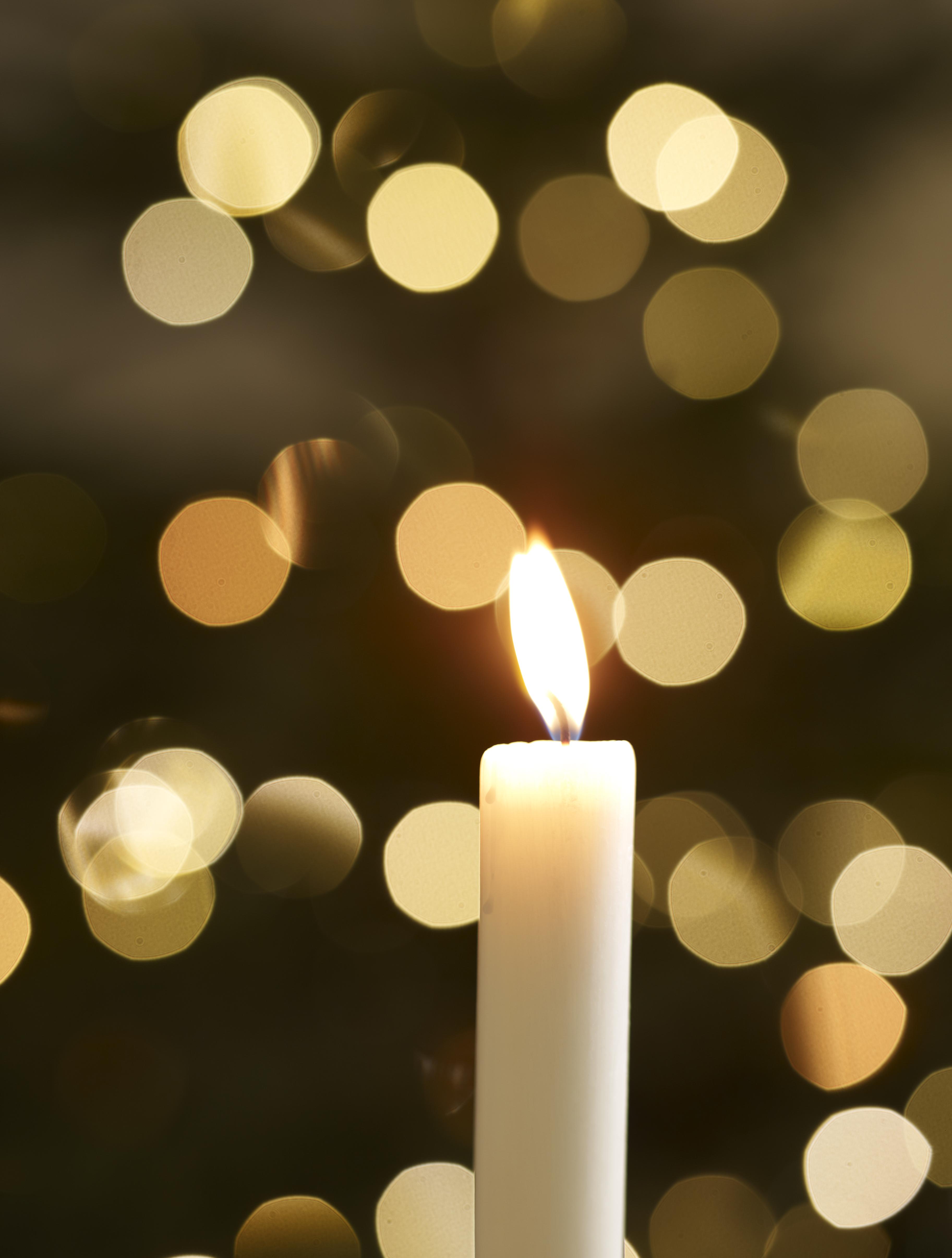 single candle with christmas lights in background