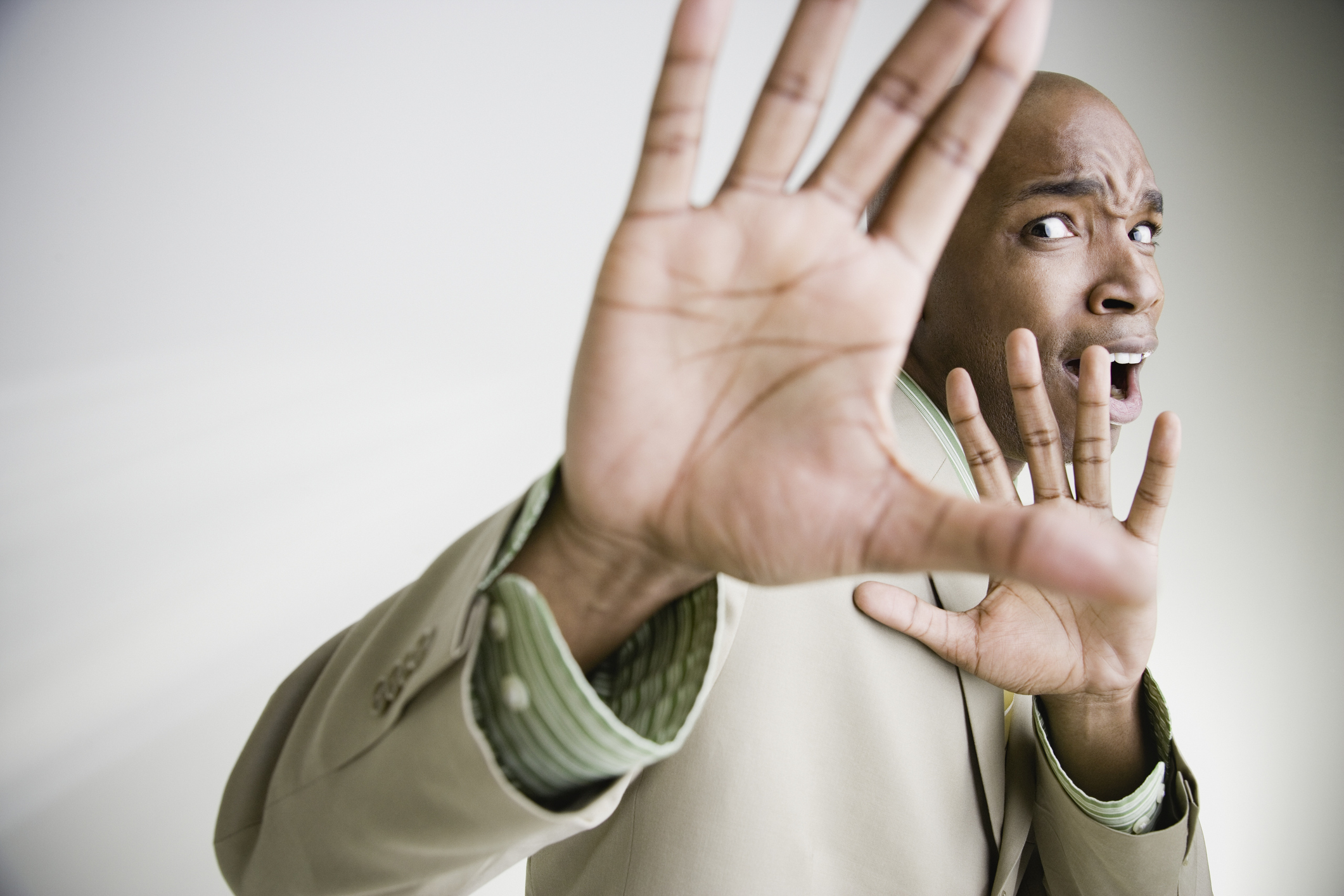 African businessman cowering with hands up