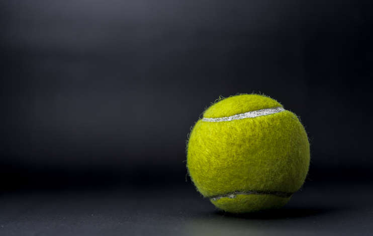 Close-Up Of Green Tennis Ball Against Gray Background