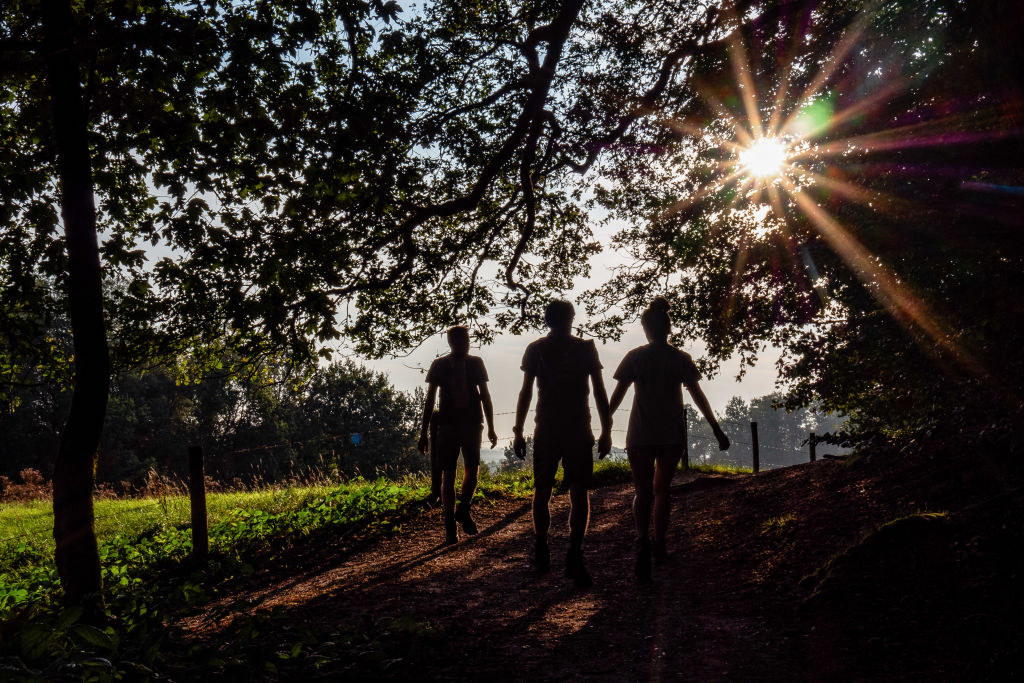 Three people are seen hiking on a very warm morning...