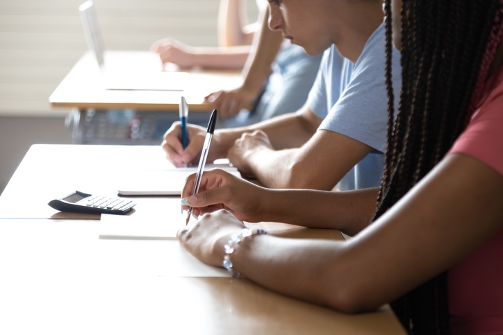 Students taking notes during test in classroom